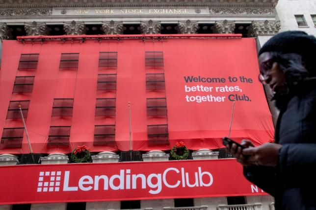 A woman looks at her phone as she passes by a Lending Club banner on the facade of the the New York Stock Exchange December 11, 2014. REUTERS/Brendan McDermid/File Photo